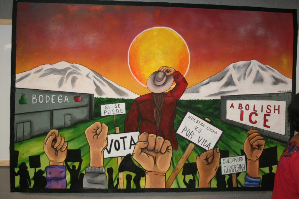 A painting that depicts a person looking at the sunrise, with a bodega building in the background. There are signs that say "Abolish Ice" and "Vota" and hands raised in solidarity in the foreground. 